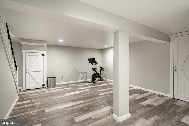 exercise room featuring recessed lighting, wood finished floors, baseboards, and a barn door