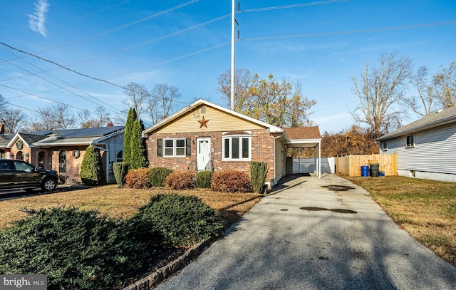 view of front facade with brick siding, driveway, a front lawn, and fence