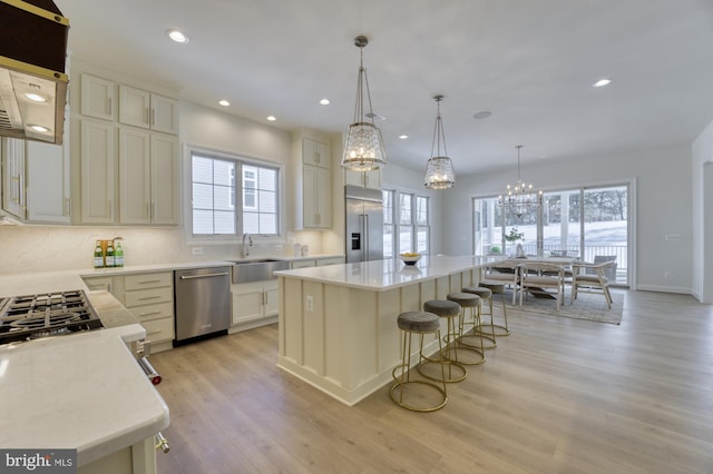 kitchen with an inviting chandelier, stainless steel appliances, a center island, a breakfast bar, and a sink