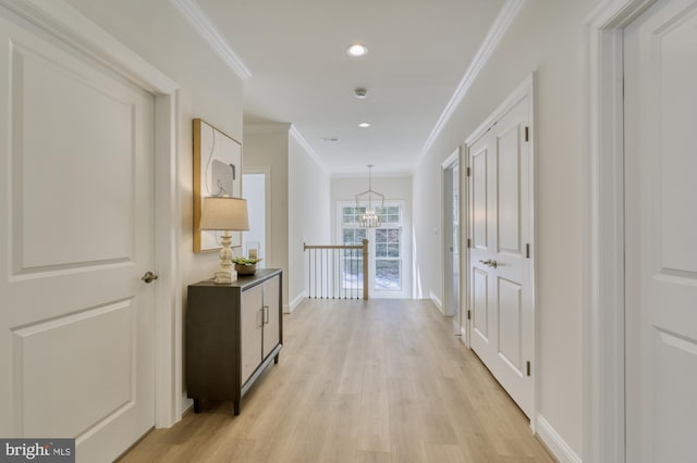 corridor with light wood finished floors, baseboards, ornamental molding, recessed lighting, and an inviting chandelier