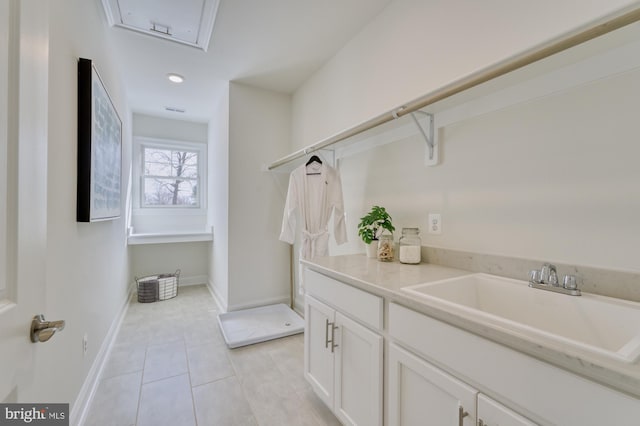 clothes washing area with light tile patterned floors, a sink, and baseboards
