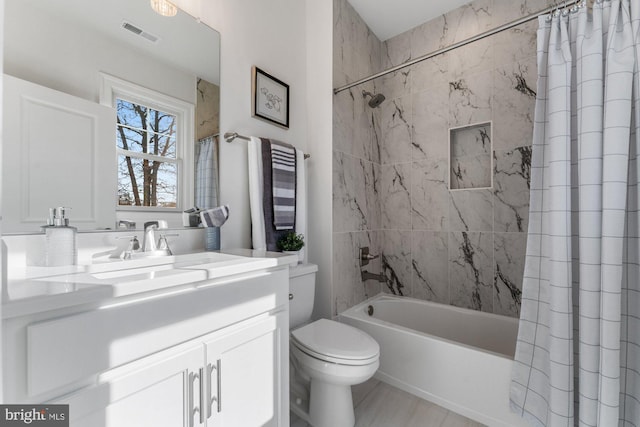 bathroom with vanity, visible vents, toilet, and shower / tub combo