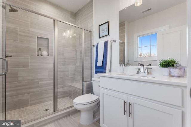 bathroom featuring toilet, a stall shower, and visible vents