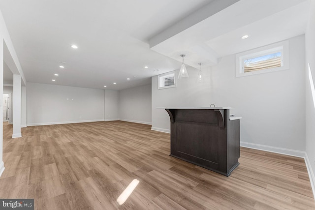 basement featuring baseboards, light wood-style flooring, and recessed lighting
