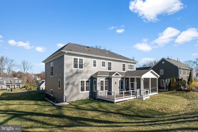 rear view of property featuring a lawn, a sunroom, and roof with shingles