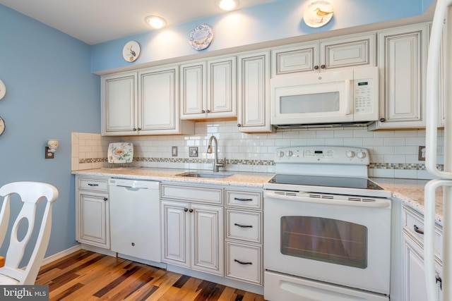 kitchen with light stone countertops, sink, backsplash, white appliances, and dark hardwood / wood-style floors