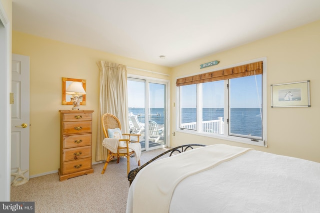 carpeted bedroom featuring a water view and access to outside