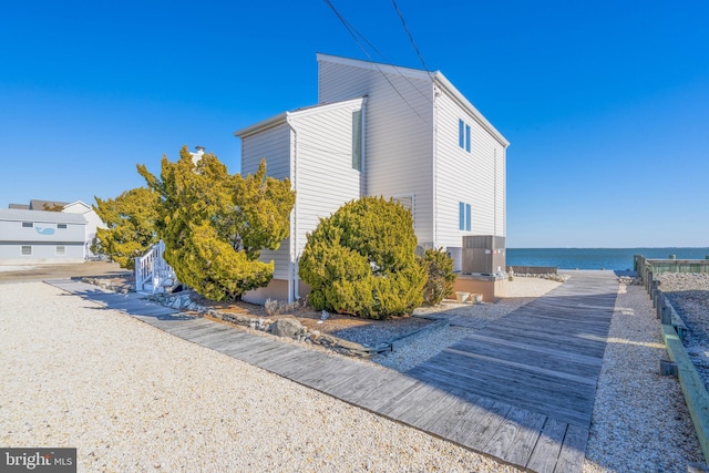 view of property exterior with central AC and a water view