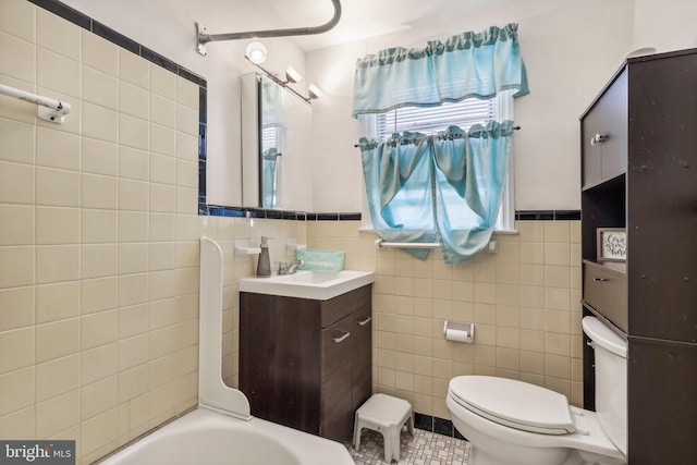 bathroom with tile walls, vanity, toilet, and a bathing tub