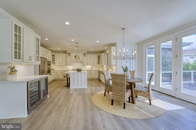 dining room with beverage cooler, recessed lighting, a chandelier, and light wood-style floors