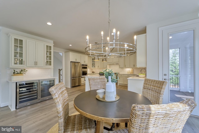 dining room featuring beverage cooler, recessed lighting, a notable chandelier, and light wood-style floors