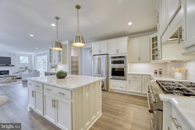 kitchen with white cabinets, glass insert cabinets, appliances with stainless steel finishes, open floor plan, and pendant lighting