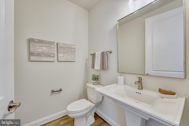 bathroom with toilet, baseboards, and wood finished floors