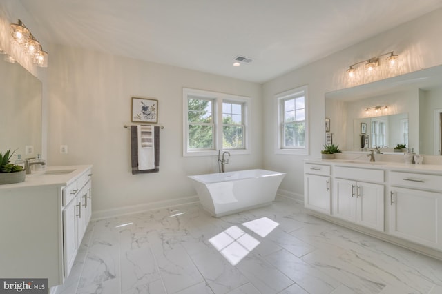 full bathroom featuring marble finish floor, a freestanding bath, baseboards, and a sink