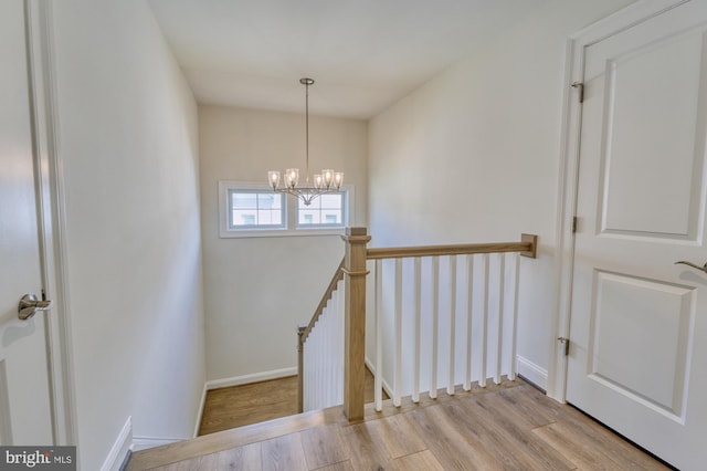 staircase with a chandelier, baseboards, and wood finished floors