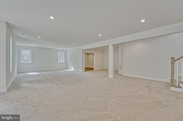 below grade area with stairs, light carpet, baseboards, and recessed lighting