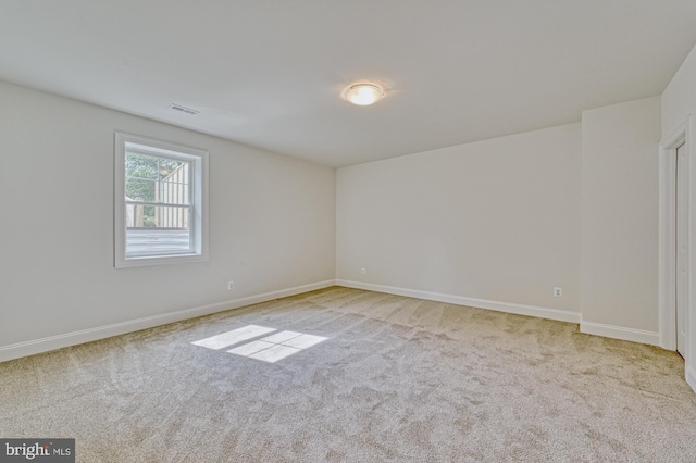 empty room featuring baseboards and light colored carpet