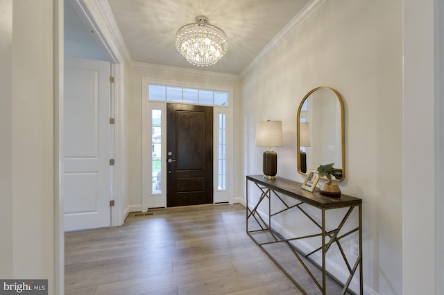 entryway with ornamental molding, light wood-type flooring, a chandelier, and baseboards