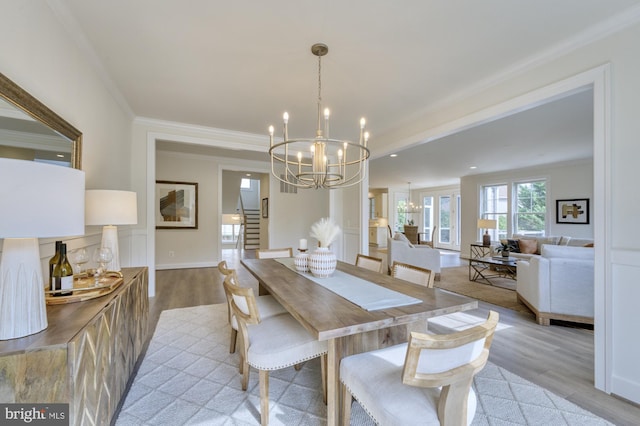 dining space featuring stairs, an inviting chandelier, light wood-style flooring, and crown molding