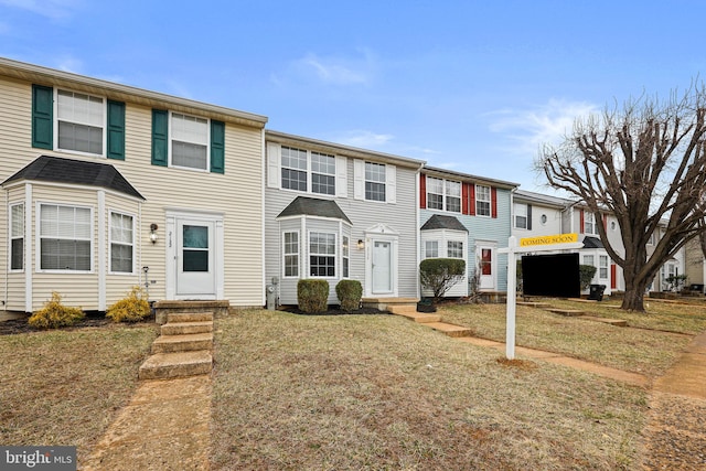 townhome / multi-family property with entry steps and a front yard