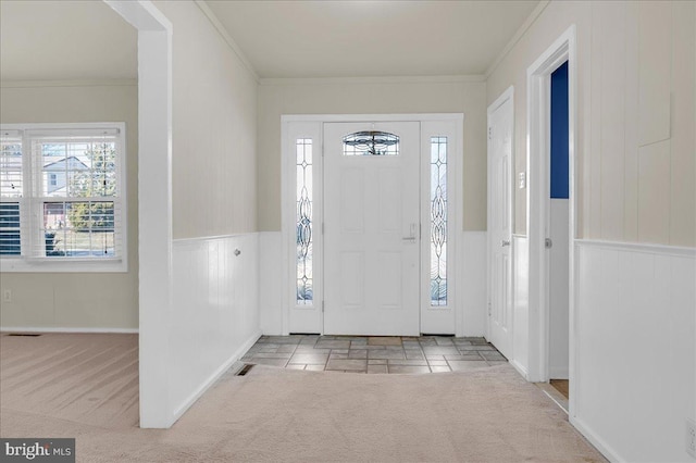 entryway featuring crown molding and light carpet