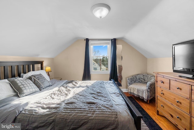 bedroom with lofted ceiling and light wood finished floors