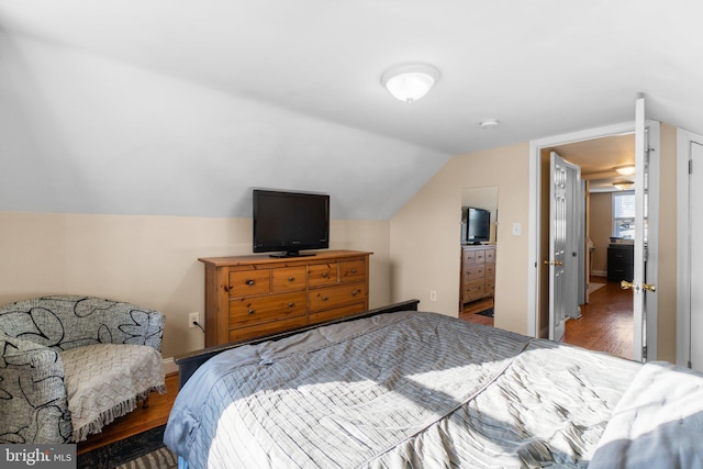 bedroom with vaulted ceiling, baseboards, and wood finished floors