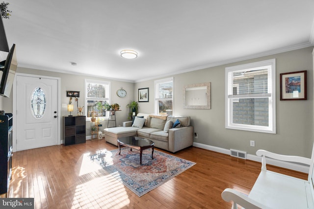 living area with light wood-type flooring, baseboards, visible vents, and ornamental molding