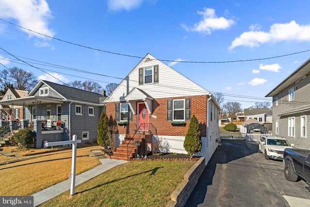 bungalow-style house with fence, a front lawn, and brick siding