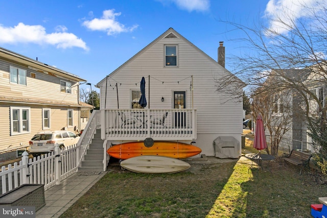 rear view of property with fence, a chimney, and a wooden deck