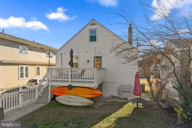 rear view of house with a deck, a yard, a chimney, and a fenced backyard