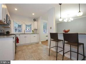 kitchen with recessed lighting, a kitchen bar, white cabinetry, and decorative light fixtures