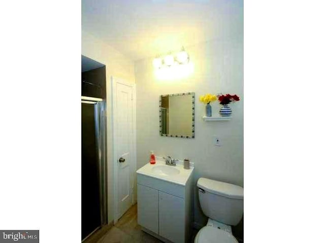 bathroom featuring toilet, a shower with door, and vanity