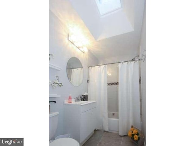 bathroom featuring toilet, a skylight, vanity, tile patterned floors, and shower / bath combination with curtain