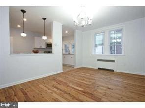 interior space featuring radiator, baseboards, an inviting chandelier, and wood finished floors