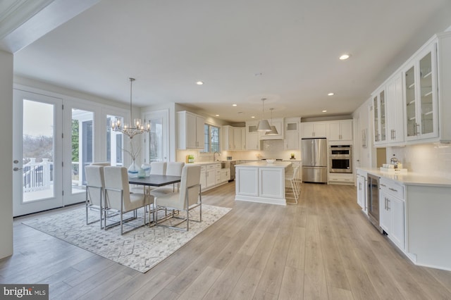 dining room with light wood finished floors, beverage cooler, an inviting chandelier, and recessed lighting