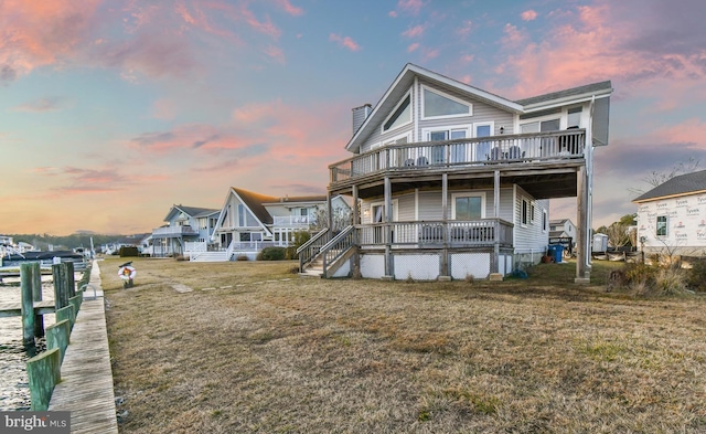 back house at dusk with a yard and a wooden deck