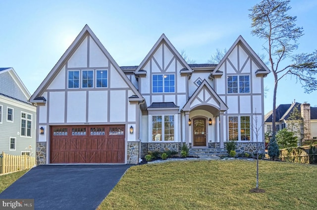 tudor house featuring stone siding, aphalt driveway, a front yard, and stucco siding