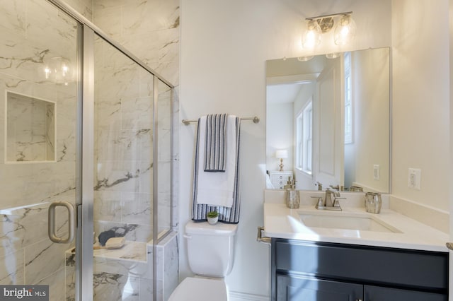 full bath featuring toilet, a marble finish shower, and vanity