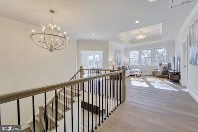 hall featuring a healthy amount of sunlight, an inviting chandelier, light wood finished floors, and an upstairs landing