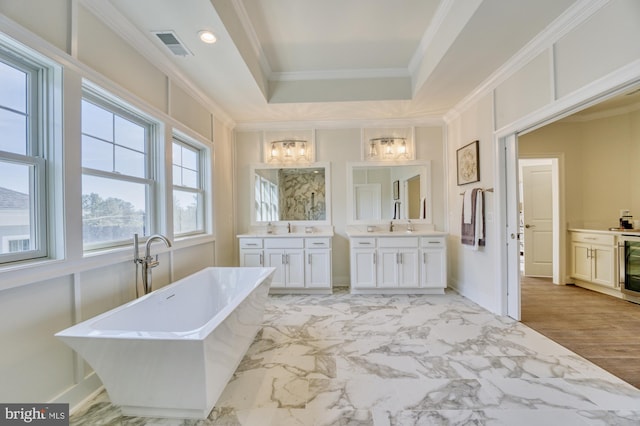 bathroom with visible vents, ornamental molding, marble finish floor, vanity, and a freestanding tub