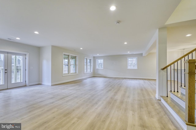 unfurnished living room with recessed lighting, french doors, light wood-style flooring, and stairs