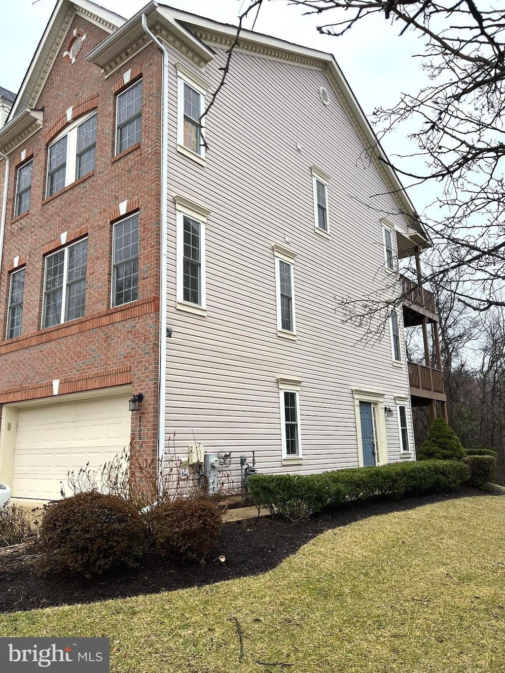 view of property exterior featuring a balcony, a garage, and a lawn