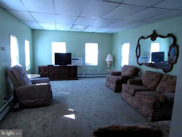 carpeted living room featuring baseboard heating and a drop ceiling