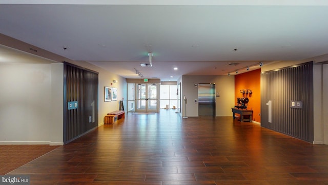 interior space with dark wood-type flooring, track lighting, french doors, and elevator