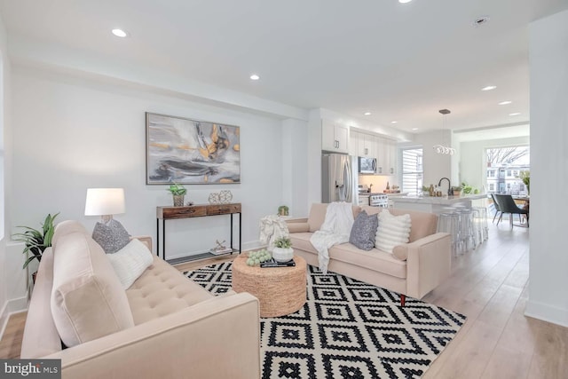 living room with light wood-style floors, recessed lighting, and baseboards