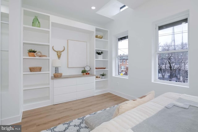 bedroom featuring light wood-style floors, multiple windows, and baseboards