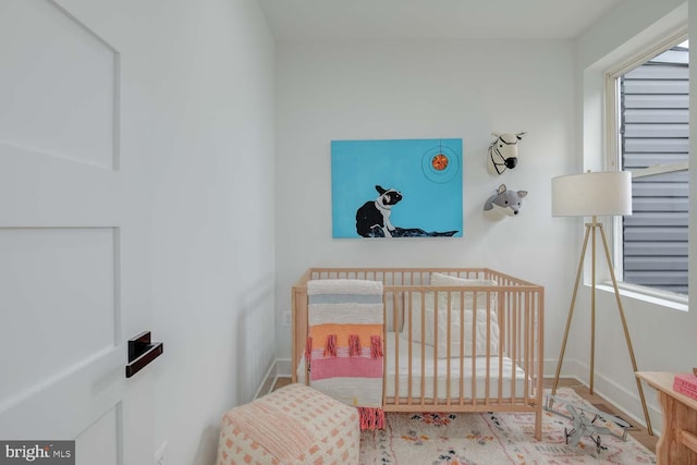 bedroom featuring a nursery area and baseboards