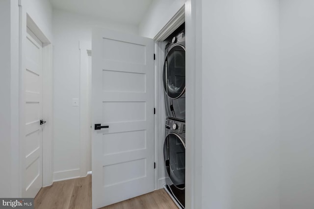 washroom featuring light wood-type flooring, stacked washer / drying machine, and laundry area