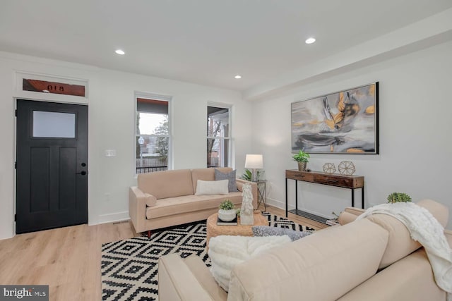 living area with baseboards, light wood finished floors, and recessed lighting